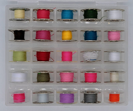 a box with multi-colored threads wound on bobbins for a sewing machine