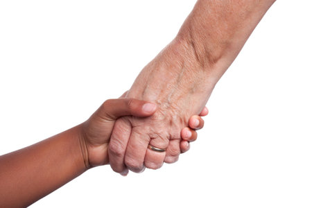Young dark skinned mixed race girls hand, holding older senior woman's hand
