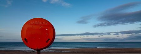 Red life bouy container Blyth beach Northumberland at duskの写真素材