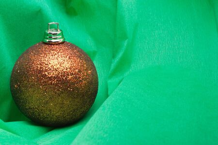 Golden Christmas bauble decoration on green crepe paper backgroundの写真素材