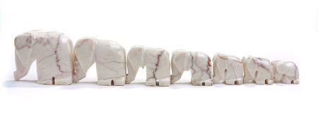 A line of seven marble elephant ornaments isolated against white background.の写真素材