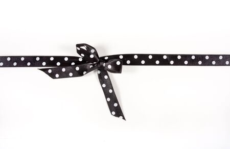 Black and white Polka Dot Ribbon tied in a bow over white card used to wrap up a xmas, birthday  or valentine present etc...の写真素材