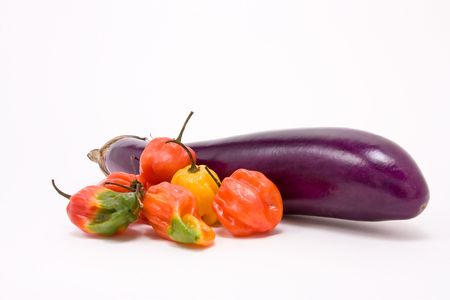 Mixed Caribbean scotch bonnet Chillies with shiny aubergine against white background from low viewpointの写真素材