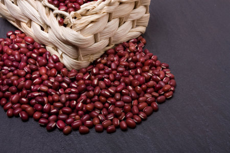 Dried cow peas overflowing from wicker basket on dark slate background.
