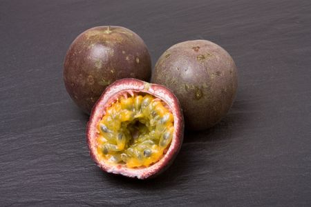 Three Passion Fruit one sliced on dark slate background.の写真素材