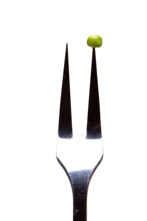 Abstract image of single pea on fork concept isolated against white.の写真素材
