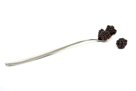 Small group of Wild hedgerow blackberries and silver spoon isolated on white.の写真素材
