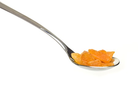 Silver spoon piled with dried fruits of apricot isolated on white.の写真素材