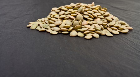 Pile of Green lentils on dark slate background .の写真素材