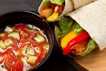 Spicy chicken wrap and pot of vibrant salsa.の写真素材