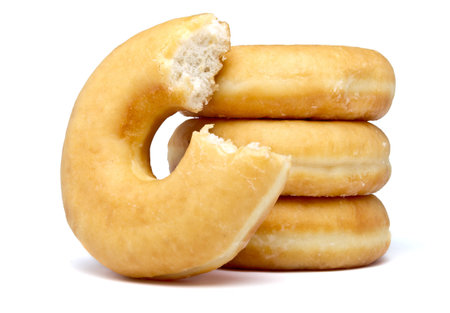 Donut stack with bite out of one isolated on white.の写真素材