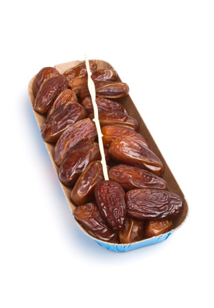 Cardboard tray of date fruits with skewer on white background.の写真素材