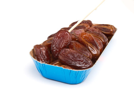 Cardboard tray of date fruits with skewer on white background.の写真素材