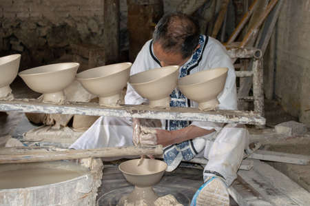 Jingdezhen, Jiangxi province / China - May 29, 2014: Porcelain Craftsman working in the Pottery workshop in Jingdezhen, China, city famous for its porcelain production and known as the `Porcelain Capital of the world`のeditorial素材