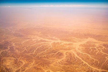 Aerial airplane view of barren Sahara desert landscape in Egypt with dried old riverbedsの写真素材