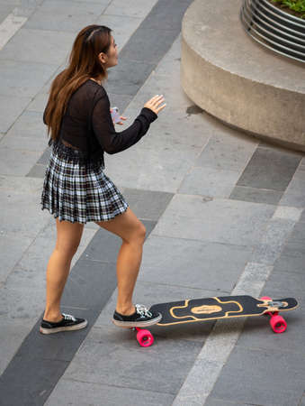 Beijing / China - August 21, 2016: Skater girl doing tricks on a skateboard in modern Sanlitun area of Chaoyang district in central Beijing, Chinaのeditorial素材