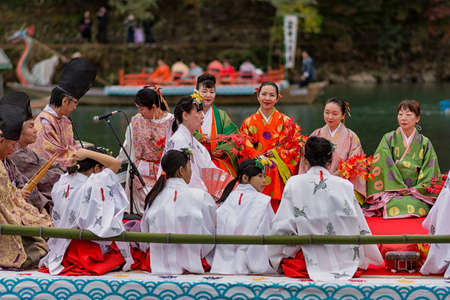 Kyoto / Japan - November 12, 2017: Traditional boat ride on Katsura River, near Arashiyama park in Kyoto, Japan. People dress in traditional clothes, sing and enjoy Autumn foliageのeditorial素材