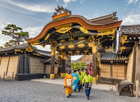 People wearing traditional Japanese clothing entering gate of shogun residence of Nijo castle, decorated with gold leaf and intricate wooden carvings in Kyoto, Japanのeditorial素材