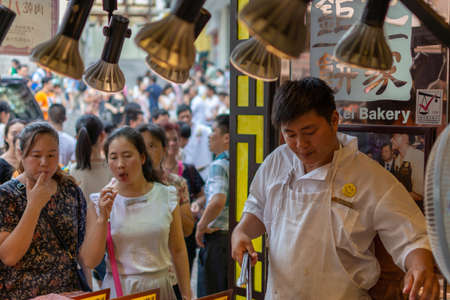 Macau (Macao SAR) / China - July 26, 2015: Vendor servicing buyers at the famous Koi Kei bakery, known for its delicious walnut cookies and almond pastry, popular as Macau souvenirs, Macau, Chinaのeditorial素材