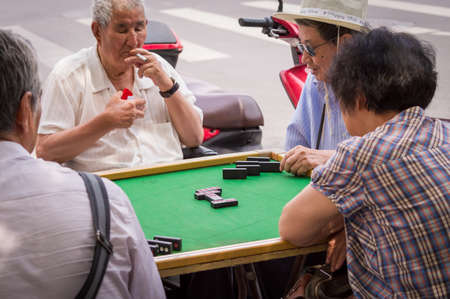 Beijing / China - June 21, 2015: People playing dominoes in the street in Beijing, capital of Chinaのeditorial素材