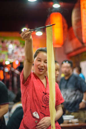 Xian / China - August 3, 2015: Restaurant staff woman preparing famous Xian noodles in Muslim quarter of the Old city of Xian in Shaanxi province, Chinaのeditorial素材