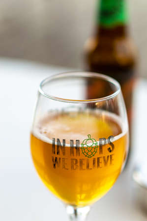 Glass of craft beer in selective focus with "In Hops We Believe" textの写真素材