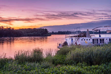 Belgrade / Serbia - June 18, 2020: Old dilapidated river raft on the bank of Danube river with colorful sunset in Belgrade, Serbiaのeditorial素材