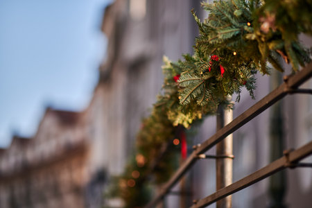 Festive holiday garland with lights and red ribbons on a railing.の写真素材