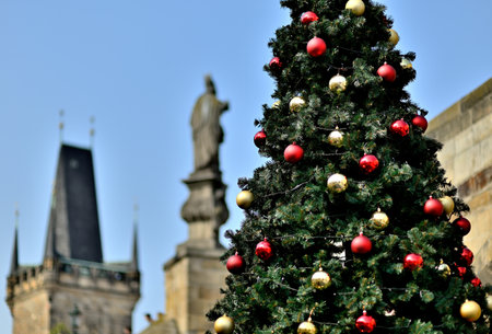 Festive Christmas tree with red and gold ornaments with historic buildings in the background in Prague, Czech Republicの写真素材