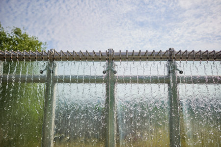 Water cascading down a glass wall under a blue sky.の写真素材