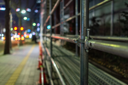 Urban street scene with scaffolding and traffic lights at night.