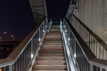 A dimly lit outdoor staircase at night with metal railingsの写真素材