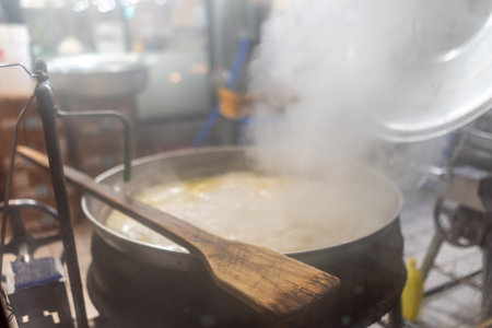 A large pot of boiling soup or stew on a stove, steam rising, wooden spoon resting on the edge, kitchen settingの写真素材