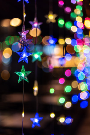 Colorful star-shaped lights hanging with a blurred background of bokeh lightsの写真素材