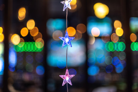 Colorful star-shaped lights hanging with a blurred background of bokeh lightsの写真素材