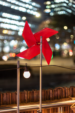 Red pinwheel against blurred city lights at night.の写真素材