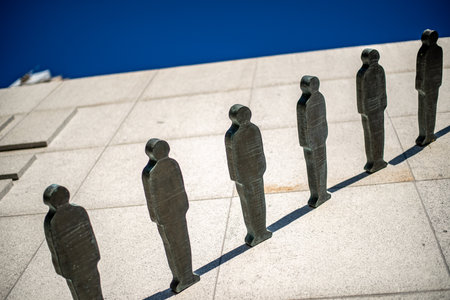Sculpture of silhouetted human figures in a line against a blue sky.の写真素材