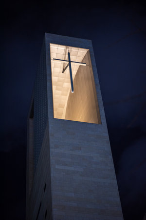 Modern church tower with illuminated cross at night.の写真素材