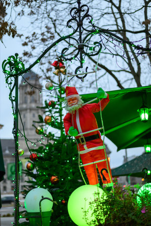 Santa Claus figure climbing a ladder with Christmas decorations.の写真素材