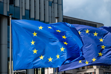 European Union flags waving in the wind against a modern buildings backdrop