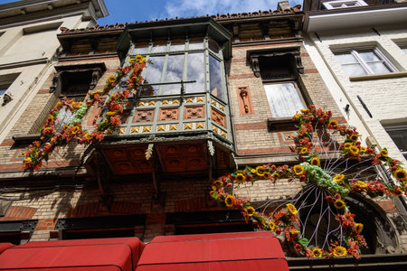 A building facade decorated with vibrant floral arrangements, featuring sunflowers and red flowers, around a vintage-style balcony.の写真素材
