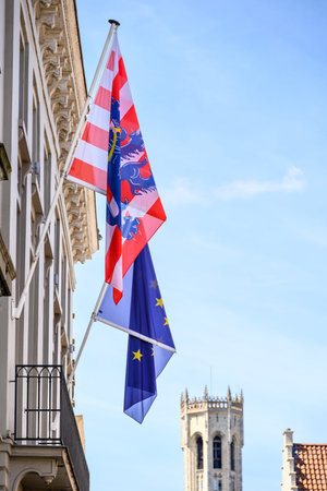 Flags of Flanders and the European Union with Belfry of Bruges in the background, in the historic...