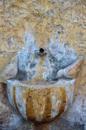 Old stone wall with a weathered, rustic fountain basin.の写真素材
