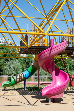 Colorful playground equipment with slides and climbing structure under a clear blue skyの写真素材