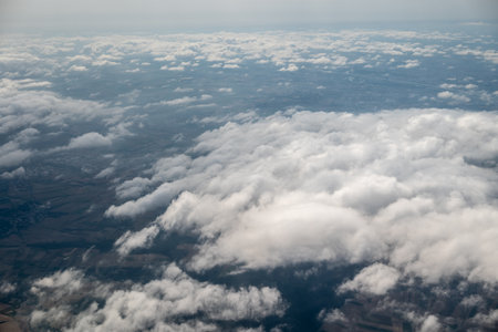 Aerial view from an airplane of fluffy white clouds under a blue sky with wispy cloudsの写真素材