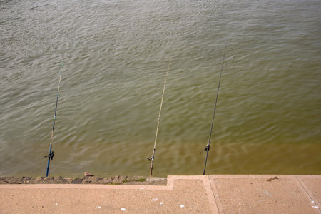 Three fishing rods set up on a riverbank, ready for fishing, on Sava river in Belgrade, Serbia on 24 October 2024の写真素材