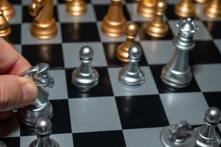 Hand moves white knight on chessboard with close up of black and white chess game pieces