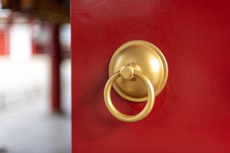 A close-up of a golden door knocker on a vibrant red door