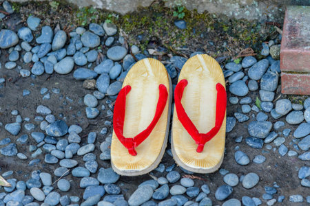 Traditional Japanese wooden sandals with red straps on pebbles
