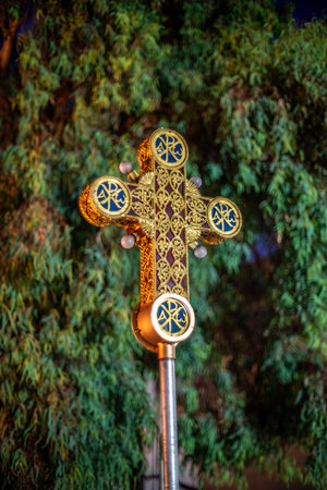 Ornate golden cross with intricate designs against a tree background.の写真素材